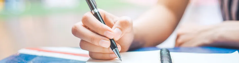 How to Write a Scholarship Letter Female student hand writing with a pen in a notebook